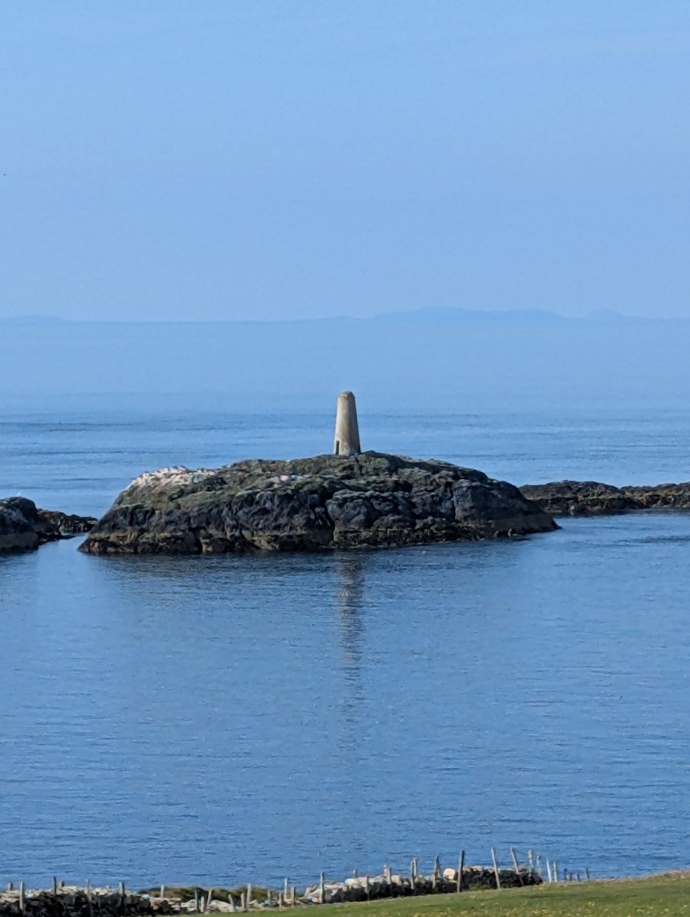 The Point — a rocky islet topped with a white stone daymark on calm water